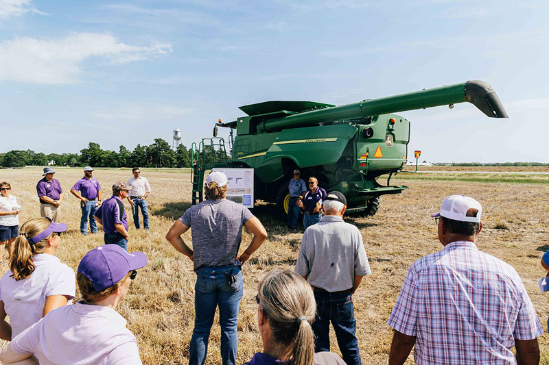 people in a field around a combine